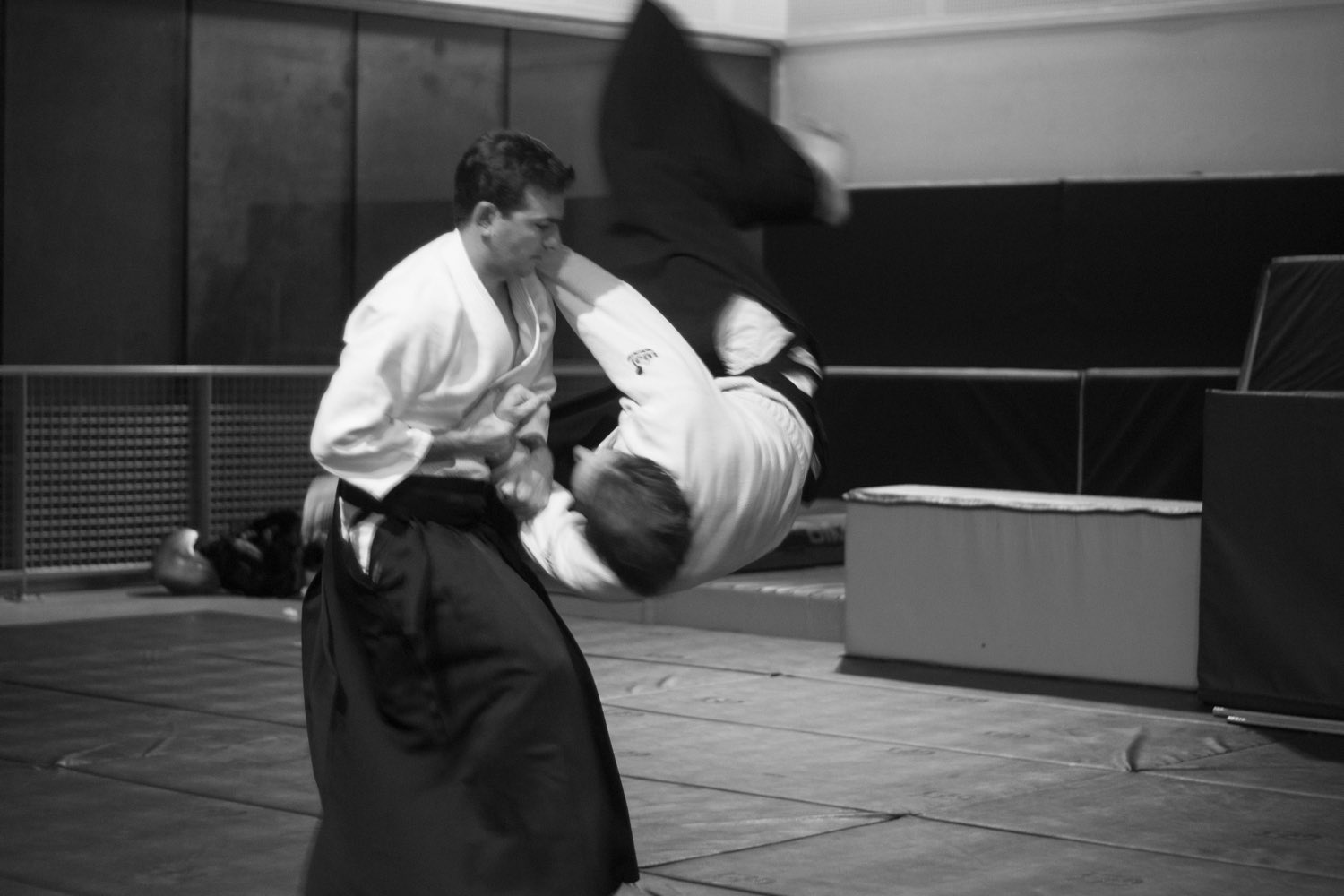 Deux pratiquants exécutent une projection d'aïkido sur le tatami du dojo