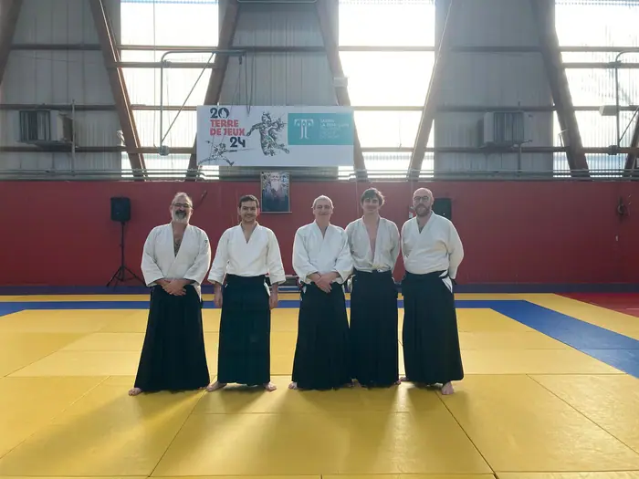 Cinq pratiquants en hakama alignés dans le gymnase
