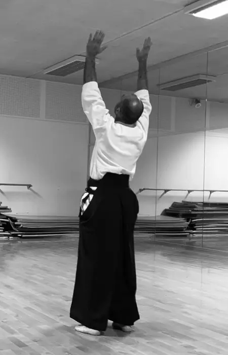 Pratiquant de dos, bras levés, en keikogi et hakama