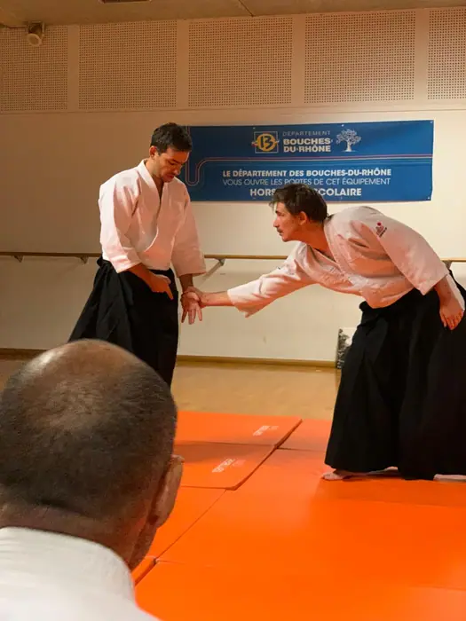 Démonstration d'aïkido lors d'un événement, sur tatamis orange