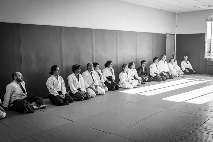 Rangée de pratiquants assis en seiza le long du mur du dojo